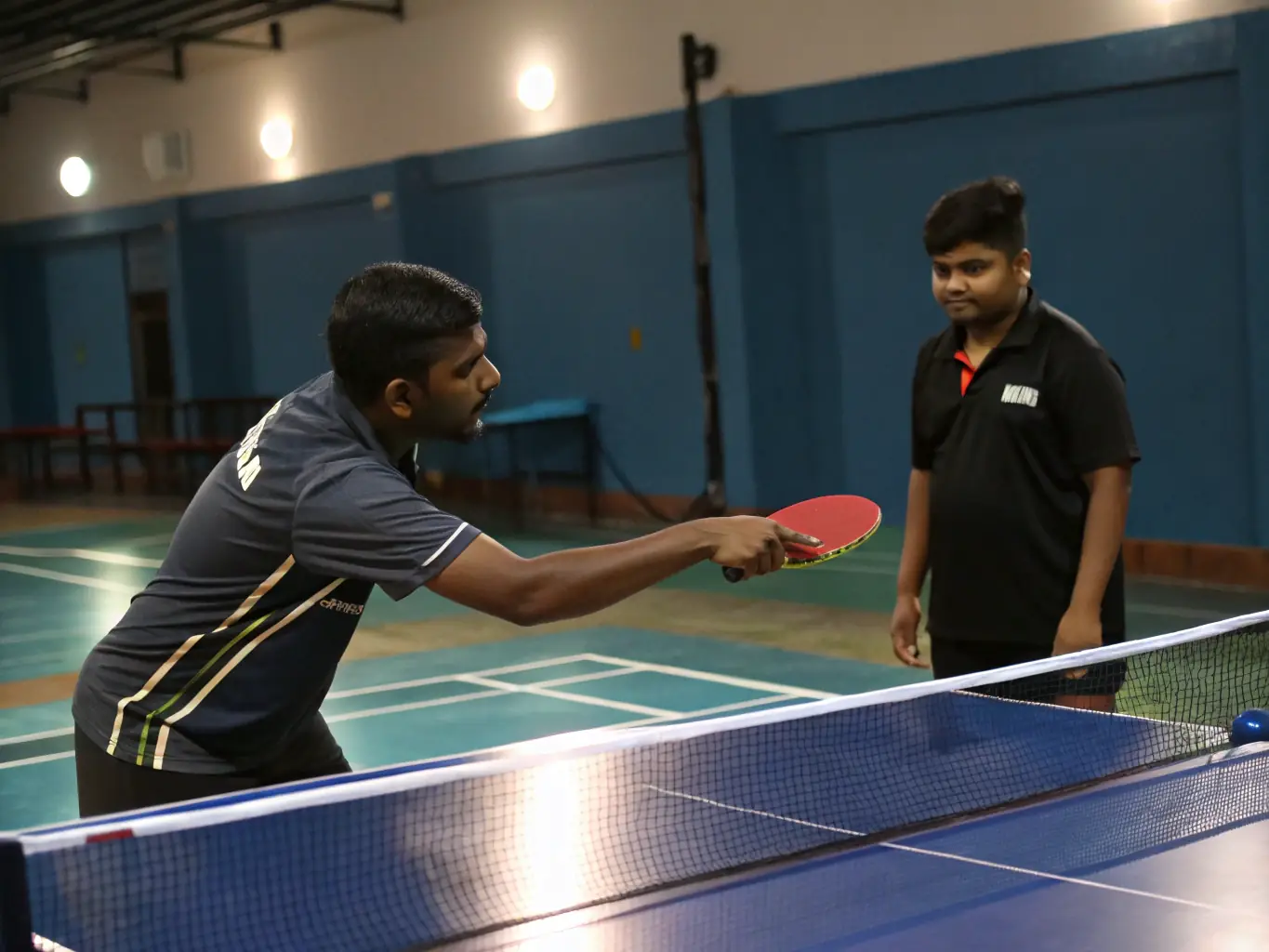 A photograph of a coach providing personalized instruction to a table tennis player at TENNIS DE TABLE CAPELLE EN PEVELLE, emphasizing the club's commitment to individual development.