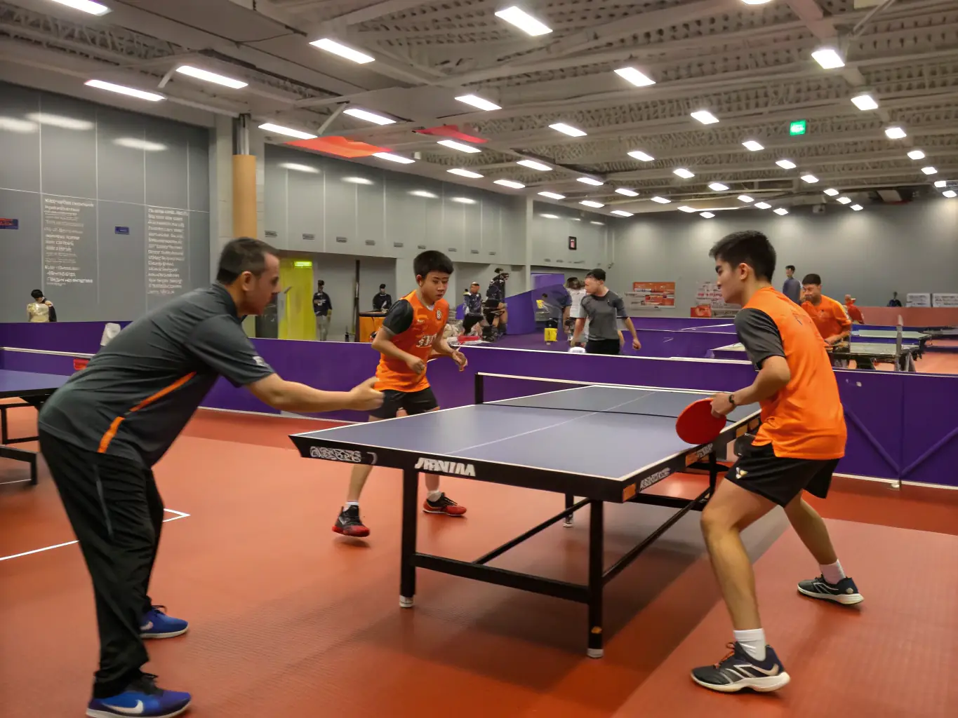 A dynamic action shot of table tennis players engaged in a training session at TENNIS DE TABLE CAPELLE EN PEVELLE, showcasing intense focus and skillful play.